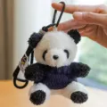 Primo piano dettagliato di un simpatico portachiavi panda di peluche con maglione. - Ciondolo Panda / Maglione Blu Scuro