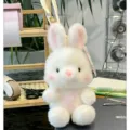 Gros plan détaillé d'un adorable lapin en peluche blanche assis doucement sur un bureau. - Lapin Blanc