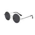 Gros plan de lunettes de soleil rondes classiques à monture en métal et verres sombres. - Aiguille en argent