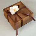 Exquisite detail view of the wooden gift box adorned with a delicate white phalaenopsis flower. - White Orchid + Brown Ribbon + Wooden Box / 20x20x10CM