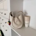 Minimalist cream hobo shoulder bag for women, stylish PU leather saddle bag with strawberry charm. - With Pendant / Off White