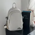 Lässiger minimalistischer grauer Nylon-Minirucksack, vielseitige Umhängetasche für moderne Damen. - Mit Anhänger / Grau