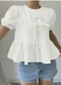 Detailansicht der eleganten weißen Kurzarmbluse mit Schleifen und Schößchensaum. - S / Oberteile / Schwarz