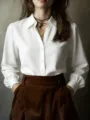Detailed view of a classic white long sleeve button down shirt paired with stylish brown trousers. - White