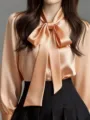 Nahaufnahme des eleganten champagnerfarbenen Satin Blusenkragens mit Schleife Detail. - S / Oberteile / Orange