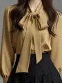 Close-up of elegant khaki pussy-bow blouse detail with graceful neck bow and buttons. - Khaki