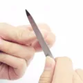 Detail shot of stainless steel nail file in use for precise manicure and nail care. - Silver