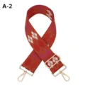 Detailed view of wide embroidered replacement bag strap with red argyle pattern and gold hardware. - A-2