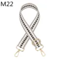 Nahaufnahme des verstellbaren schwarz-weißen Fischgräten-Taschenriemens mit goldenen Metallclips. - Stil M22