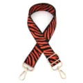 Close-up detail of red and black zebra pattern replacement bag strap with gold metal hardware. - No. 8 Orange