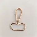 Gros plan d'un mousqueton pivotant en métal doré rose pour sacs et accessoires d'artisanat. - Or