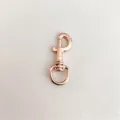 Detalle en primer plano de un mosquetón de metal oro rosa, gancho giratorio para bolsos y llaveros. - Oro Brillante