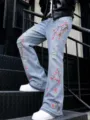 Dettaglio dei jeans da uomo azzurri strappati con ricamo floreale rosa e vestibilità a zampa. - Taglia S / Blu