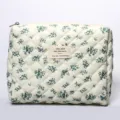 Detailed view of the quilted cosmetic bag with blue floral pattern and woven label. - Gourd Flower Floral Cosmetic Bag