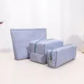 Close-up detail of blue and white striped canvas cosmetic storage bags set. - Blue Pleated Cosmetic Bag Set (Large, Medium, Small)