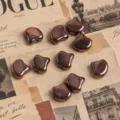 Close-up of metallic copper double-hole ginkgo beads, perfect for DIY jewelry crafting details. - 10g Approx 44 Beads / Antique Bronze Coffee