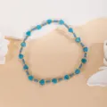 Gros plan de perles de cœur en turquoise bleue et d'espaceurs métalliques dorés sur fond neutre - Bleu foncé