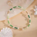 Primo piano di un delicato braccialetto di perle con perline verdi e dorate colorate. - 5#