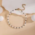 Detail shot of white rice bead and black round bead layered bracelet with gold extension chain. - Pearl Black