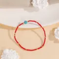 Close-up detail of the red seed bead bracelet with turquoise center stone and gold spacer accents. - Style #9
