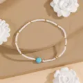 Minimalist beaded bracelet detail featuring white seed beads and a central blue stone. - Style #10