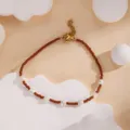 Close-up detail shot of brown seed beads and white pearls bracelet with a gold metal clasp. - Brown