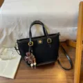Schwarze Wildleder-Tasche mit Schultergurt, elegante Freizeithandtasche mit Blumenanhänger. - Mit Anhänger / Schwarz
