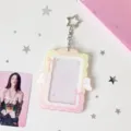 Acrylic photocard holder detail showing angel wings and pink bow design with star keychain. - Yellow