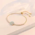 Pulsera ajustable chapada en oro con dije de flor azul claro y circonitas cúbicas brillantes. - Pulsera Ajustable de Flor Azul (TS0278) / Dorado