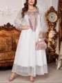 Gedetailleerd uitzicht op de elegante witte maxi-jurk met fijne borduursels en mouwen. - Wit Gaas