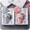 Vue détaillée du coffret cadeau tasse en céramique marbrée avec couvercle et cuillère, design. - Bord Doré Flamant Rose Coffret Cadeau Tasse + Couvercle & Cuillère / Rose