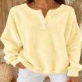 Vista detallada de la sudadera Henley de forro polar amarillo con botones blancos y tela suave. - S / Tops / Amarillo