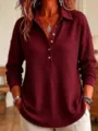 Close-up detail of women's waffle knit long sleeve polo shirt texture and button closure. - Burgundy