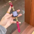 Gros plan sur le bracelet de montre en velours rouge avec chaînes en métal à étoiles d'or. - Rouge Boucle Dorée