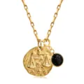 Détail de collier pendentif signe astrologique Balance doré avec pierre brillante foncée. - Balance