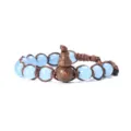 Gros plan d'un bracelet tressé avec des perles bleu clair et un pendentif en bois en forme de gourde. - Calcédoine Bleue