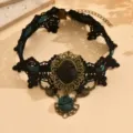 Primo piano di choker in pizzo nero vintage con ciondolo floreale bronzo e rosa. - Ciano (YR4053-1)