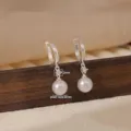Primer plano detallado de pendientes de aro de plata con diamante y perla colgante. - Hebilla de Oreja Plateada Strass Perla