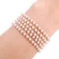 Primer plano detallado de una pulsera de cuentas de cristal rosa de múltiples hilos. - Blanco