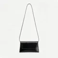 Vue rapprochée des détails du sac à bandoulière en cuir verni noir minimaliste et élégant. - Noir