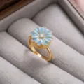 Primer plano detallado del anillo dorado con flor de esmalte azul en caja de terciopelo. - Anillo (J0357) / Azul Dorado