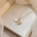 Detailaufnahme einer doppelten Herz-Halskette mit funkelndem Zirkon und weissem Inlay im Tüll. - Gold Doppelherz Stil (X1266)