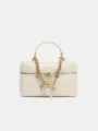 White leather vanity bag detail, featuring gold chain strap and cute metal charms. - White