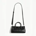 Black leather shoulder bag with adjustable strap, top handle and stylish buckle detail. - Black