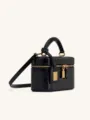Detailed view of black crocodile embossed mini vanity box bag with gold tone hardware and handle. - Black