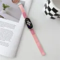 Λεπτομερής εικόνα ροζ πλεγμένου λουριού smartwatch σε σκηνικό με φυτό και κούπα. - Ροζ
