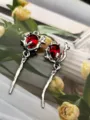Gedetailleerde opname van de zinklegering rozen tak hanger met rode kristallen druppel accessoire. - Rood
