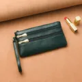 Monedero largo de piel graneada verde oscuro con cremalleras múltiples y correa de muñeca. - Verde