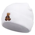 White knitted beanie with cute bear embroidery, winter warm wool hat detail shot, cozy style. - White