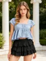 Detailaufnahme des stylischen gestuften Rüschen-Kuchenrocks und blauen Tops im Freien. - S / Unterteile / Schwarz
